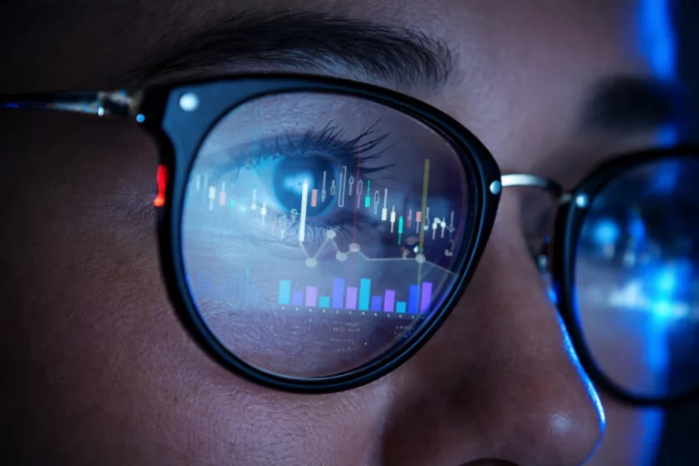 Close-up of eyes in glasses reflecting data charts and financial analytics, representing a holistic view of customer data